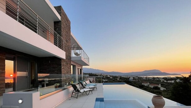 Una casa moderna con piscina sul tetto, un balcone con poltrone relax e una vista panoramica sul paesaggio.