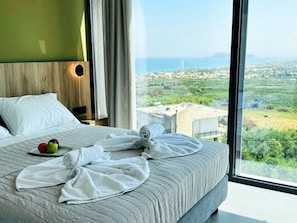 Ein Hotelzimmer mit einem großen Bett, Blick auf die Landschaft und einem Holzkopfende.