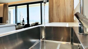 Eine moderne Küche mit Spüle aus Edelstahl, einer Wand mit Holzvertäfelung und Blick auf die Stadt durch große Fenster.