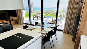 A modern kitchen with a dining area, large windows, and a view of the sea. - Skyline Ocean - 20PL 8BD 6BA, 3min to the beach (GR9M+6V5 Platanias, Greece)