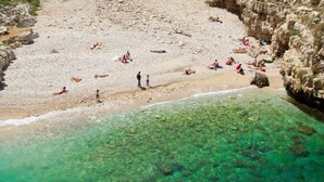 Una playa con aguas cristalinas y terreno rocoso.