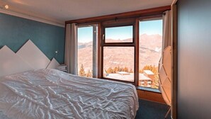 A bedroom with a bed, a window with a mountain view, and a wooden headboard. - 50m from ski slopes, 3rd floor, tv, 33m², Les Arcs (Les Arcs)