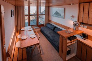 A cozy cabin interior with a dining table set for four, a sofa, and a kitchen area with a kettle and utensils. - 50m from ski slopes, 3rd floor, tv, 33m², Les Arcs (Les Arcs)