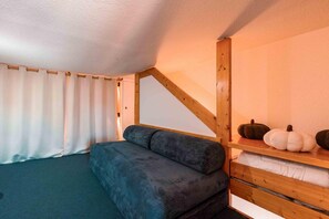 A cozy room with a wooden ceiling, a dark blue sofa, white curtains, and a shelf with pumpkins. - 50m from ski slopes, 3rd floor, tv, 33m², Les Arcs (Les Arcs)
