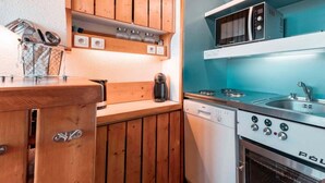 A compact kitchen with wooden cabinets, a built-in microwave, a stove, and a dishwasher. - 50m from ski slopes, 3rd floor, tv, 33m², Les Arcs (Les Arcs)