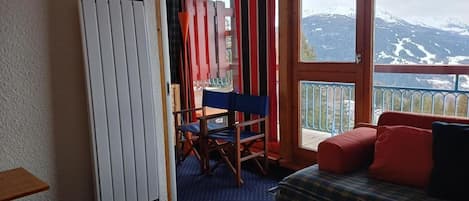 Una habitación con cama, mesa, silla y ventana con vistas a la montaña.