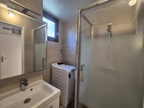Une salle de bain équipée d’un lavabo, d’un miroir et d’une douche à parois de verre.