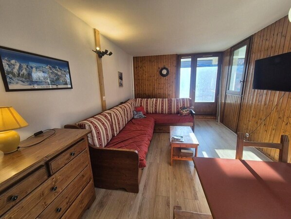 Une pièce chaleureuse avec un canapé en bois, une petite table, une lampe et une commode en bois.