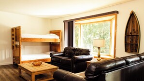 A room with a bunk bed, leather sofa, wooden coffee table, and a lamp. - Kings Den resort (Revelstoke)