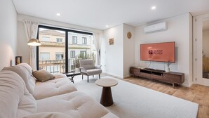 A modern living room with a sofa, a chair, a coffee table, a TV, and a balcony view.