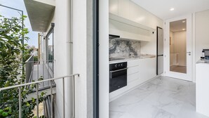 A modern kitchen with a marble backsplash, white cabinetry, and a built-in oven.