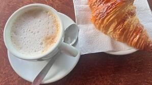 Une tasse de café et un croissant sur une table ronde.