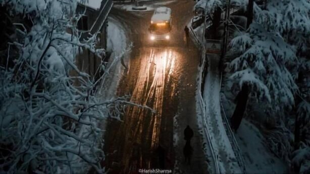 Une rue enneigée avec un bâtiment doté de nombreuses fenêtres et d’une enseigne lumineuse.