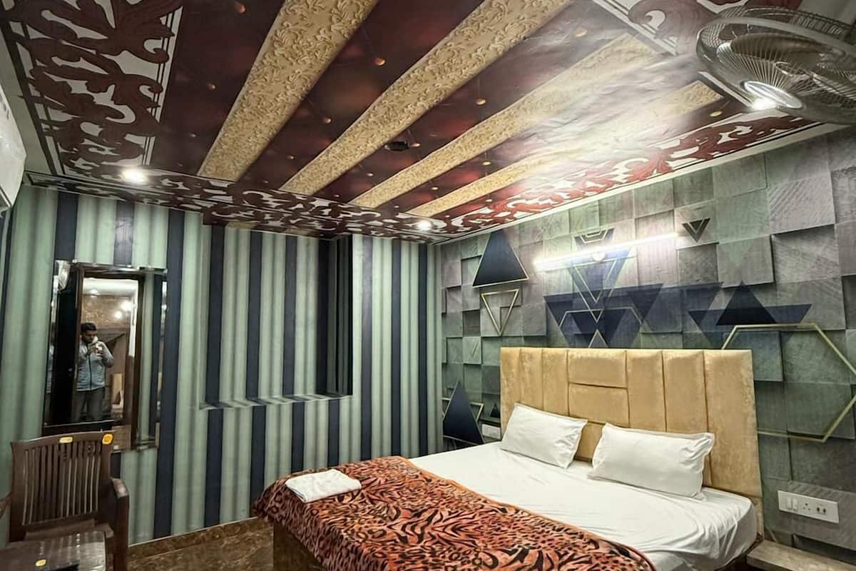 A modern bedroom with a large bed, a mirror, and a unique ceiling design.