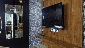 Una habitación con pared de madera, televisor montado y alfombra estampada.