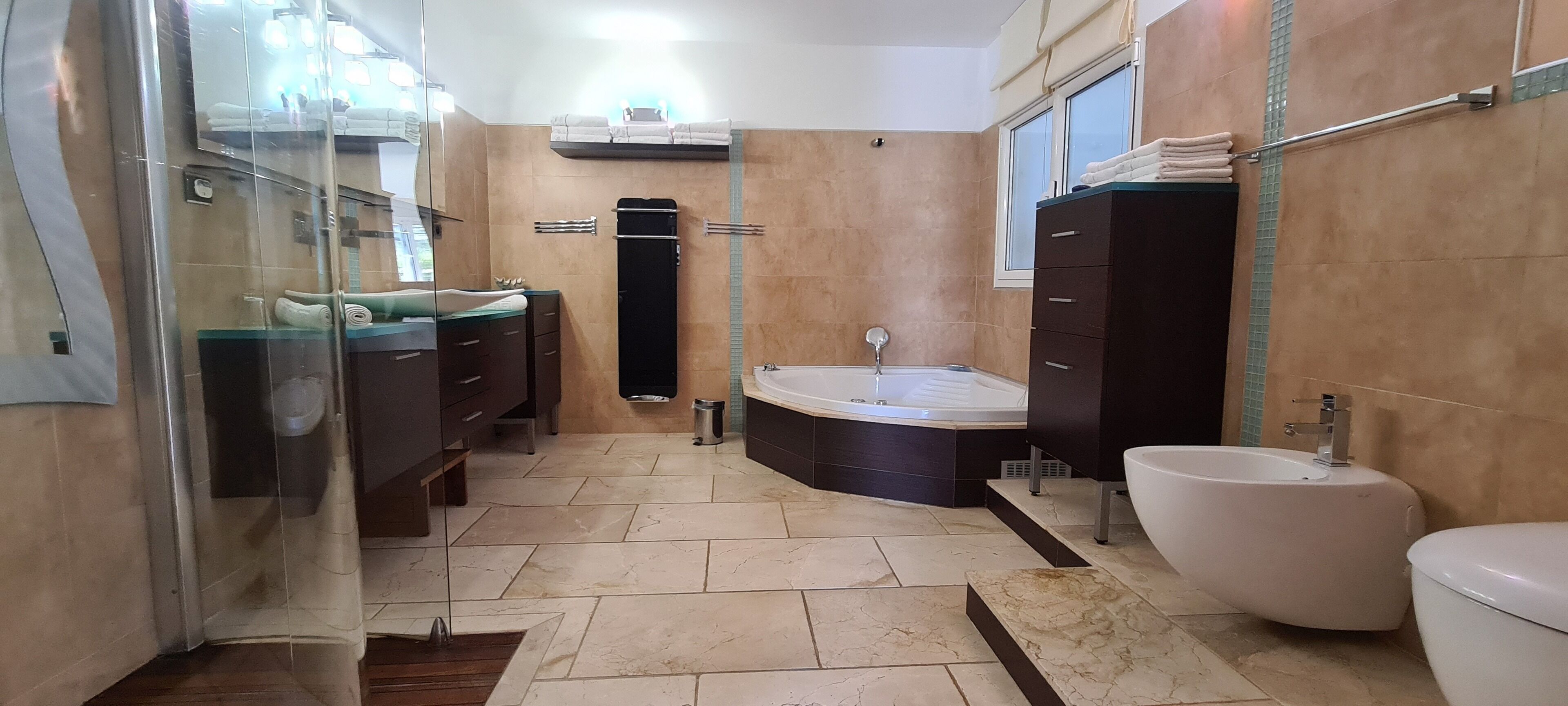 A modern bathroom with a bathtub, a toilet, a sink, and a vanity with a mirror.
