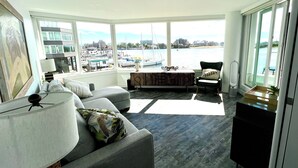 Una sala moderna con un ventanal grande, un sofá, un sillón y una mesita.