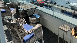 Un balcón con mobiliario de mimbre y vistas a un puerto deportivo con barcos.