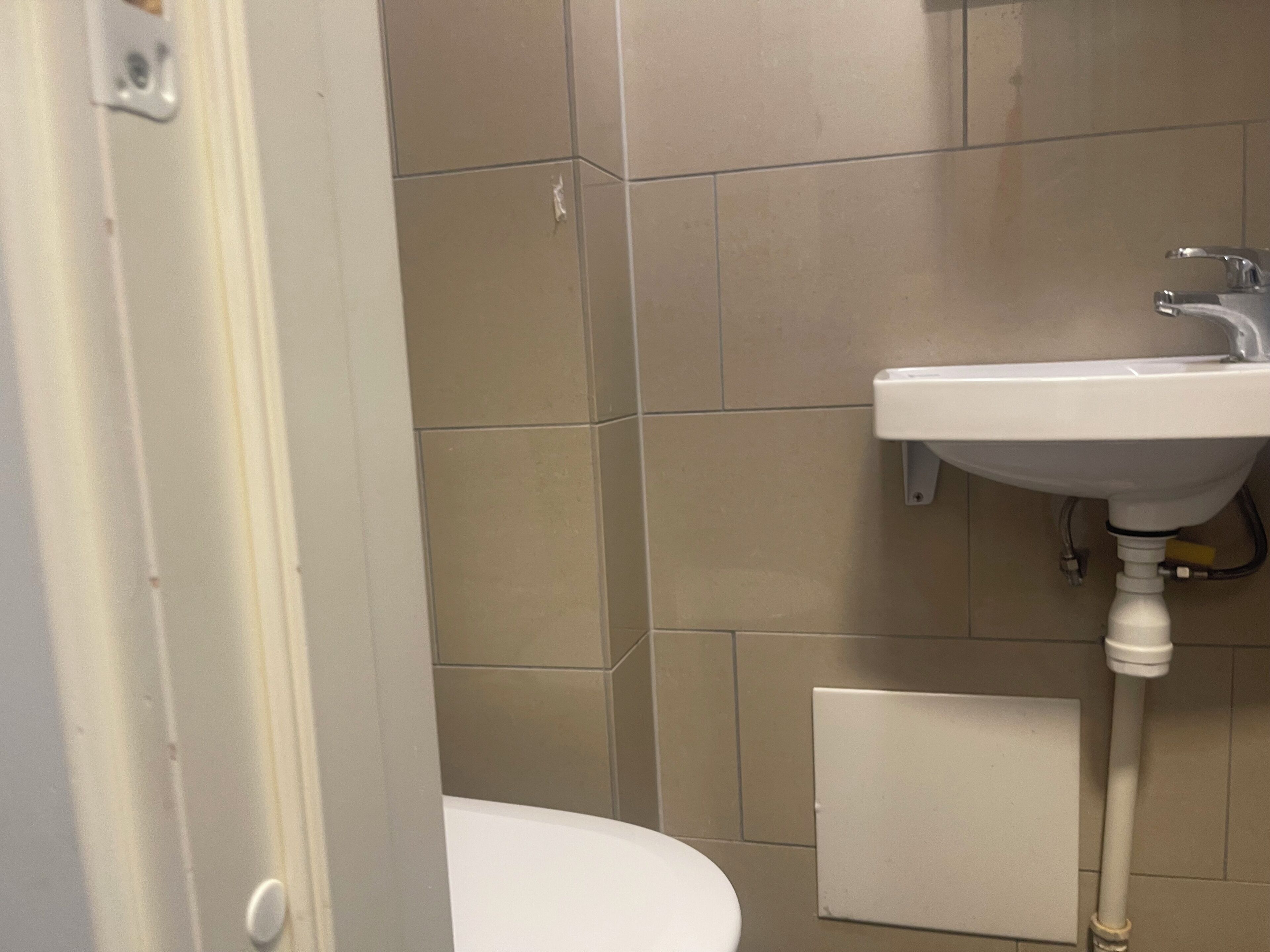 A bathroom with a white sink, a toilet, and beige tiled walls.