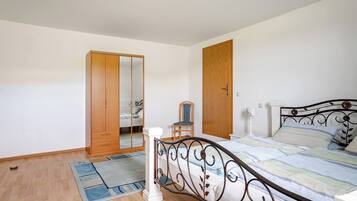 A bedroom with a bed, a wardrobe, a chair, and a nightstand.