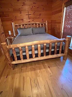 Una habitación de cabaña de madera con cama, paredes de madera y una ventana.
