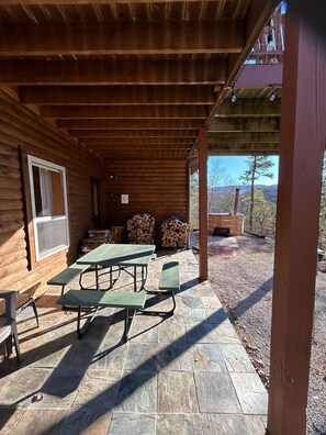 Un patio techado con mesas de picnic y vistas del paisaje circundante.