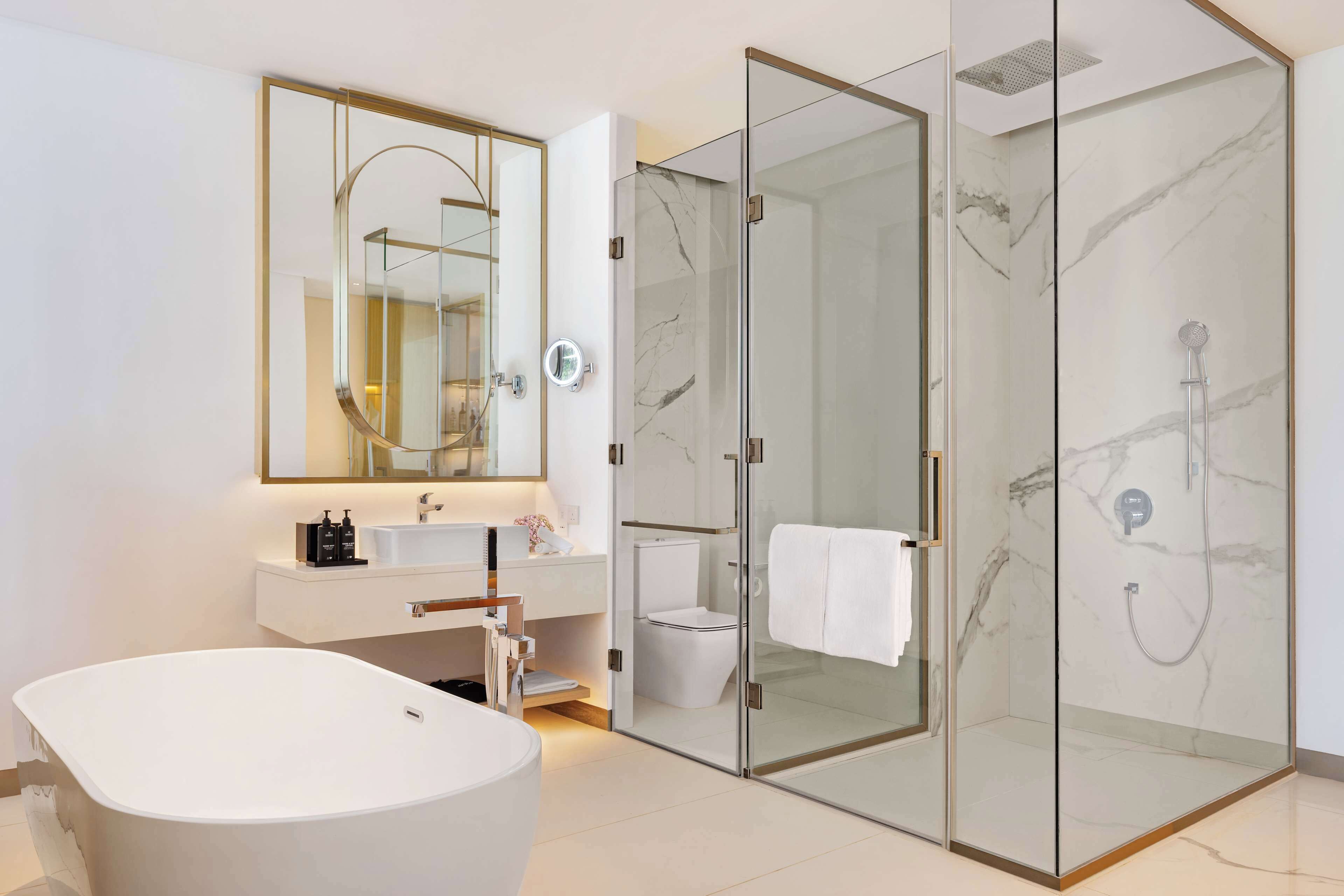 Un baño moderno con una bañera independiente, una ducha con mampara de vidrio y un tocador con espejo.