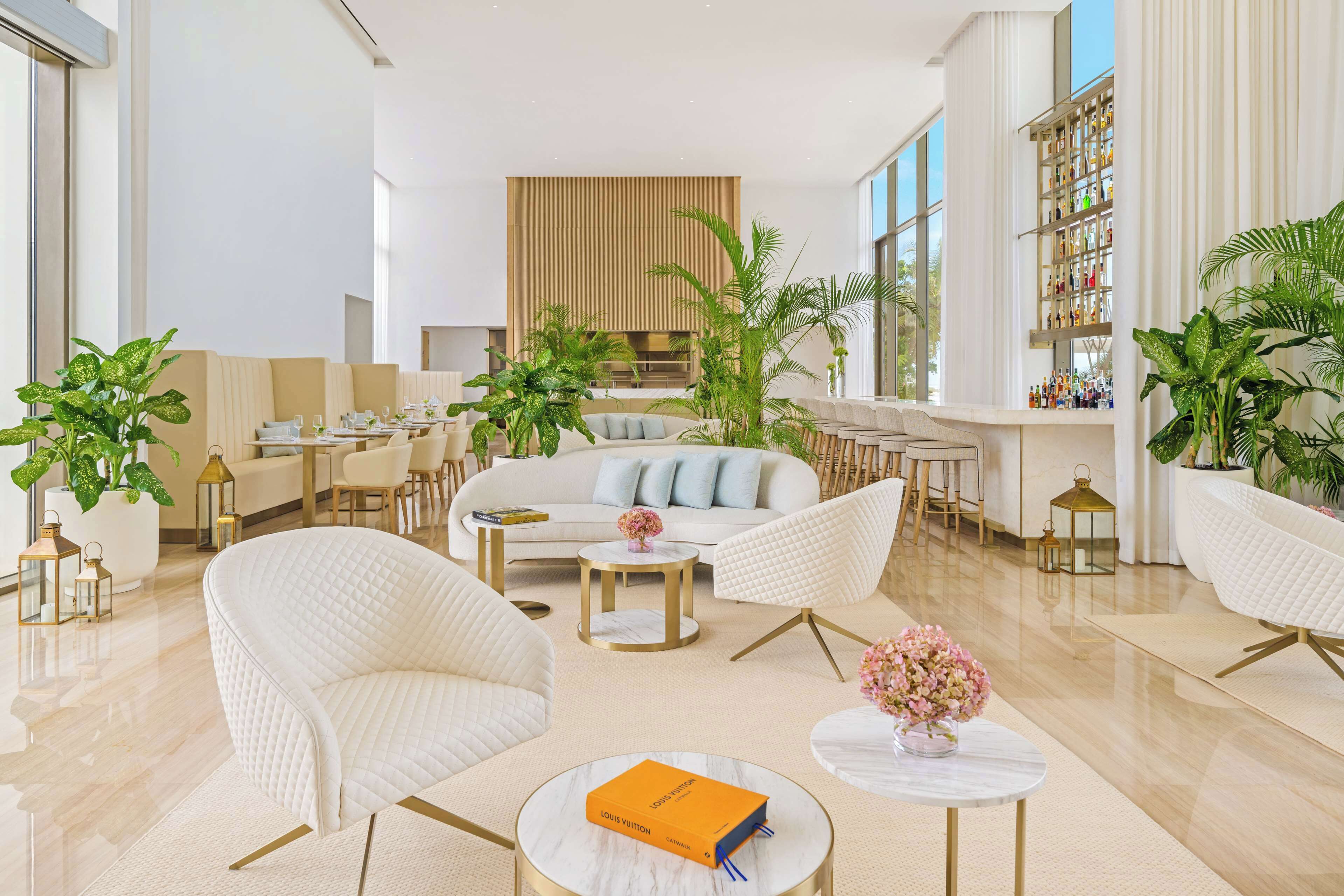 A modern hotel lobby with a central seating area, a bar, and a large window.