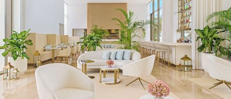 Un hall d’hôtel moderne doté d’un espace salon central, d’un bar et d’une grande fenêtre.
