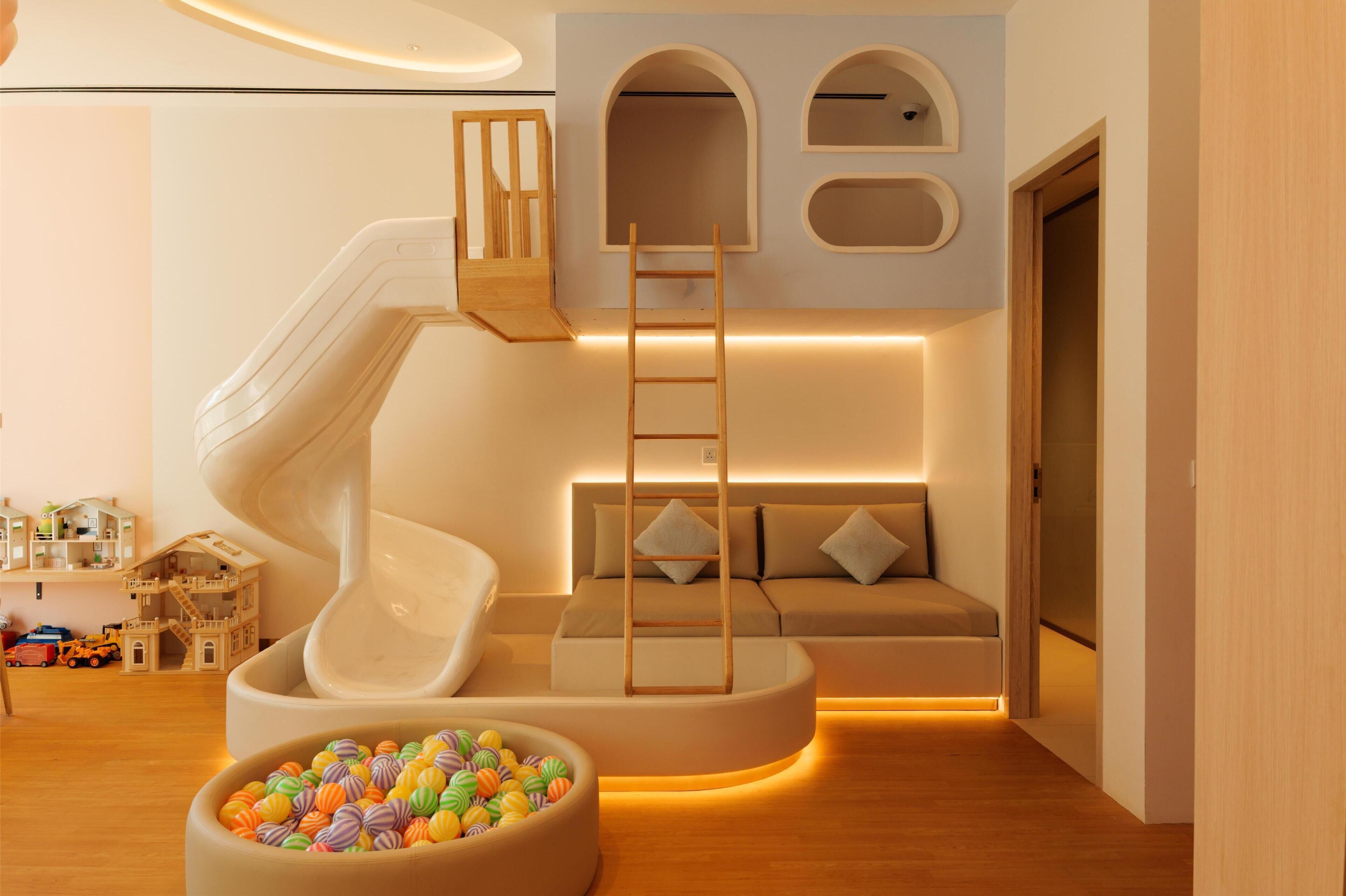A play area with a slide, a ball pit, and a sofa with a ladder.