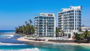 A beachfront hotel with multiple floors, a pool, and a view of the ocean.