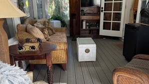 Un salon chaleureux avec des meubles en osier, un téléviseur et un appareil de diffusion en continu (streaming).