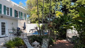 A patio area with two lounge chairs, a small table, and a decorative bird statue. - Pool, laundry, and grilling area (Key West)
