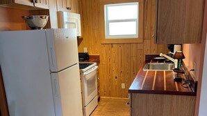 A kitchen with wooden cabinets, a refrigerator, stove, and a sink. - Pool, laundry, and grilling area (Key West)