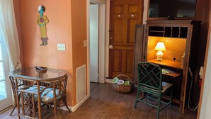 A room with a wooden floor, a glass table with chairs, a television on a wooden stand, and a door with a wooden panel. - Pool, laundry, and grilling area (Key West)