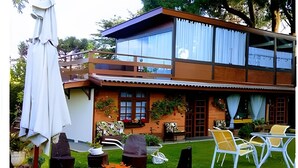 Una casa moderna de dos pisos con balcón, zona de estar exterior y una chimenea.