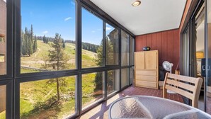 Un balcón con vistas a un paisaje montañoso, un armario de madera y una silla.