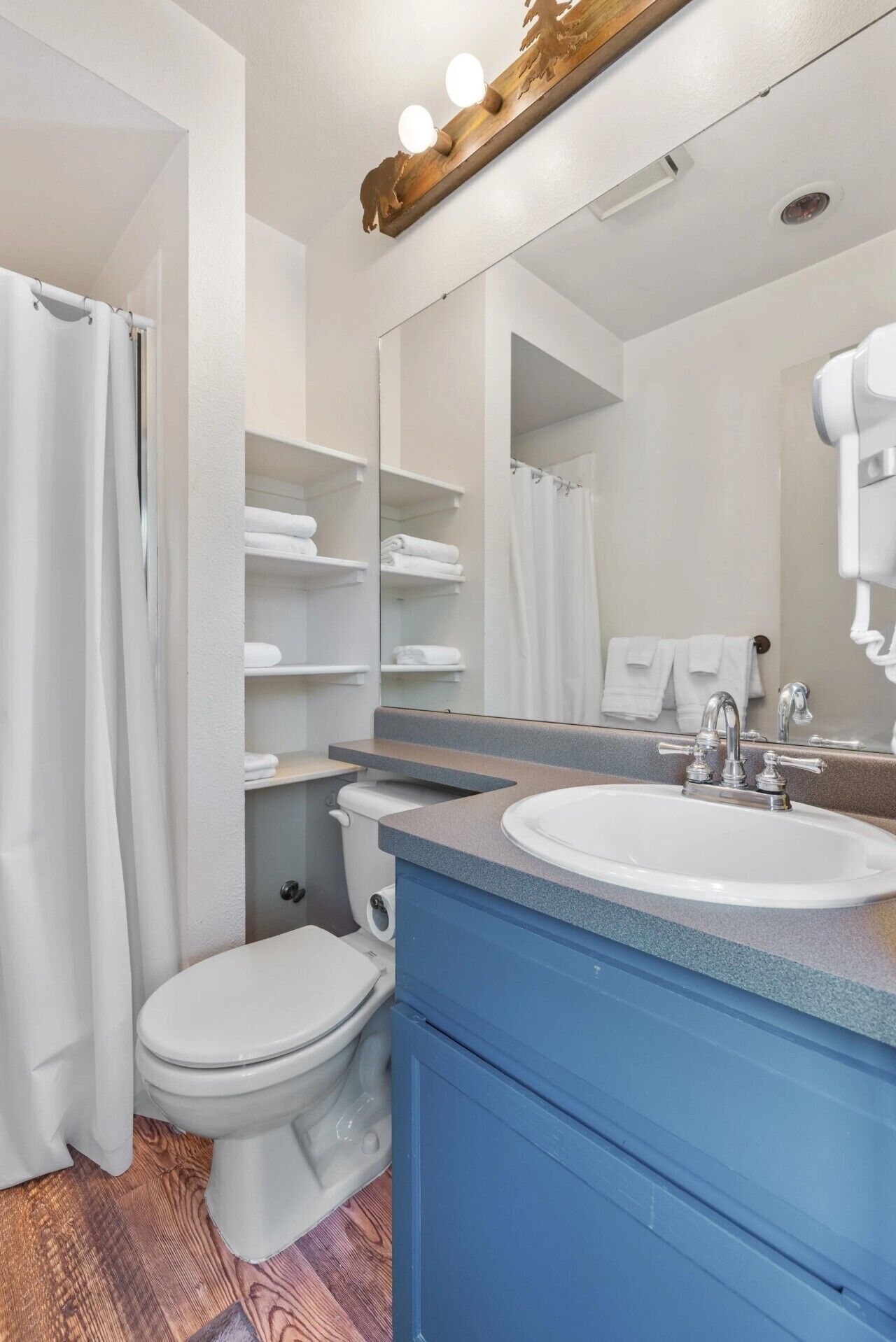 A bathroom with a white toilet, a sink with a mirror above it, and a shower curtain.
