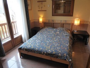 Ein Schlafzimmer mit einem Bett, zwei Nachttischen, einem Fenster mit Vorhängen und einer Wandlampe.