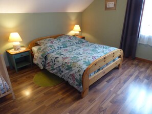 Une chambre à coucher avec un lit en bois, deux tables de chevet avec des lampes, un tapis vert et un tableau encadré au mur.