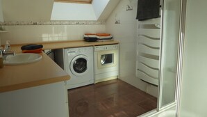 Een kleine keuken met dakraam, een wasmachine en een inbouwoven.