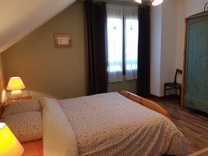 Een slaapkamer met een bed, een stoel, een lamp en een kledingkast.
