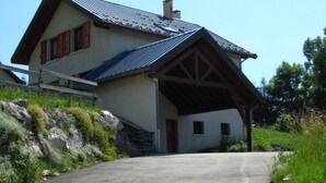 A two-story house with a sloped roof, a covered porch, and a stone wall. - House-Comfort-Mountain view-4 etoilles-Mobility bath (Villard De Lans)