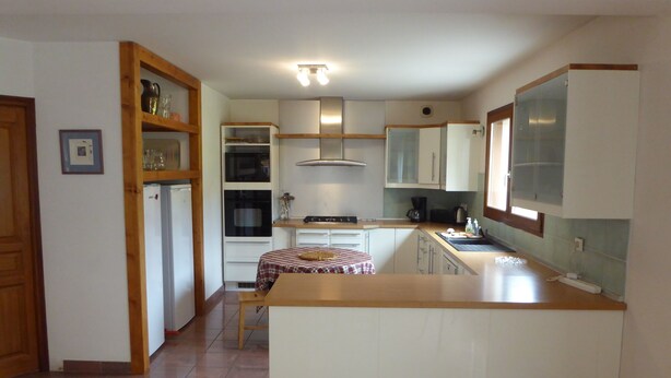 A compact kitchen with white cabinets, a central island, and a tiled floor. - House-Comfort-Mountain view-4 etoilles-Mobility bath (Villard De Lans)