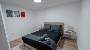 A bedroom with a bed, nightstands, a lamp, and three wall art pieces. - Spacious and Stylish Apartment Perfect for Your Getaway in Beverly! (Beverly)