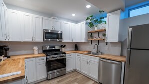 A modern kitchen with white cabinets, stainless steel appliances, and a wooden countertop. - Spacious and Stylish Apartment Perfect for Your Getaway in Beverly! (Beverly)