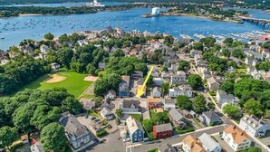 An aerial view of a coastal town with residential houses, a marina with boats, and a prominent lighthouse. - Spacious and Stylish Apartment Perfect for Your Getaway in Beverly! (Beverly)