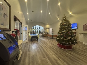 Um quarto espaçoso com mesa de bilhar, árvore de Natal e mesa de sinuca.