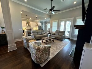 A spacious living room with a large sofa set, a coffee table, and a ceiling fan. - Walk to Beach | Private Pool | Sleeps 8 (Long Beach)