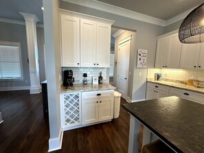 A kitchen with white cabinets, a granite countertop, and a dark wooden floor. - Walk to Beach | Private Pool | Sleeps 8 (Long Beach)